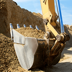 Godet d’une pelle mécanique transportant de la terre sur un chantier d’excavation.