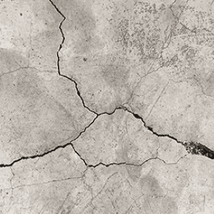 Surface de béton avec des fissures visibles nécessitant une réparation.
